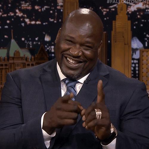 Jimmy Kimmel Live gif. Wearing a dark blue suit with a light blue striped tie, a cheerful Shaquille O'Neal makes bobbing finger guns at us.